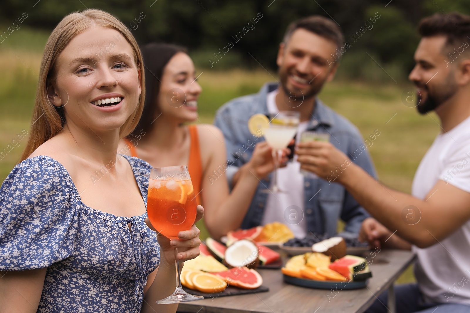 Photo of Friends having cocktail party outdoors. Happy woman with glass of drink, selective focus