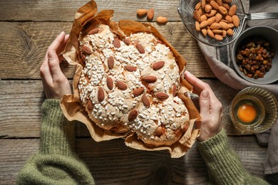 Photo of Woman with delicious Italian Easter dove cake (traditional Colomba di Pasqua) at wooden table, top view