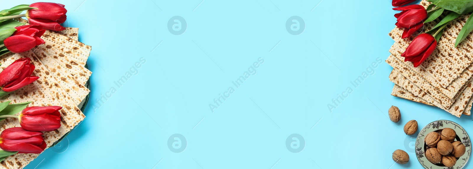 Image of Matzos and flowers on light blue background, flat lay with space for text. Passover (Pesach) Seder