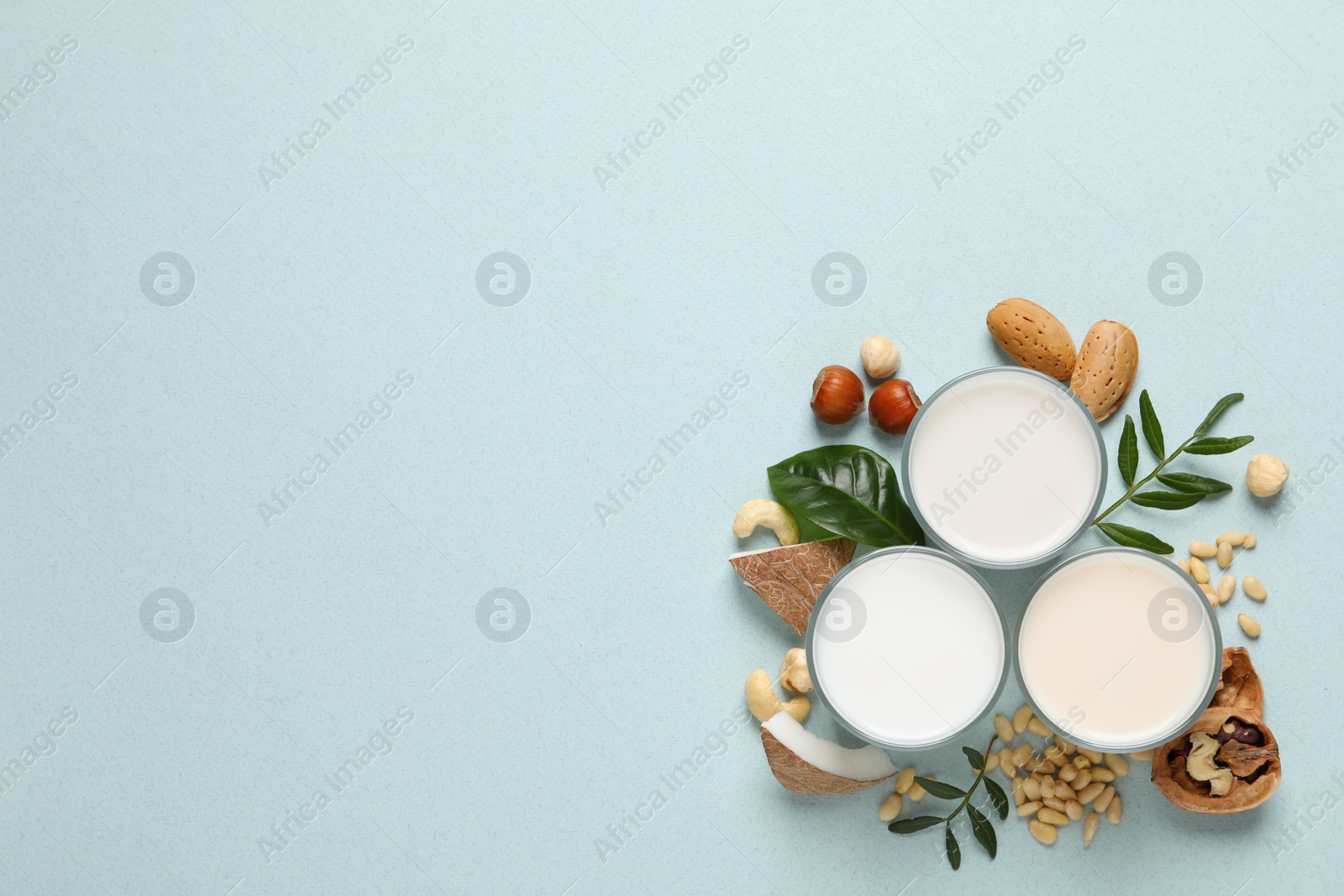 Photo of Vegan milk and different nuts on light background, flat lay. Space for text
