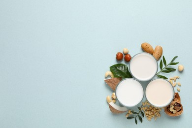 Vegan milk and different nuts on light background, flat lay. Space for text