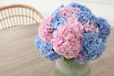 Vase with beautiful hydrangea flowers on wooden table indoors, closeup. Space for text