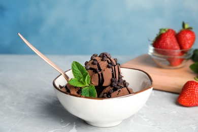 Photo of Bowl of chocolate ice cream and strawberry on grey table, space for text