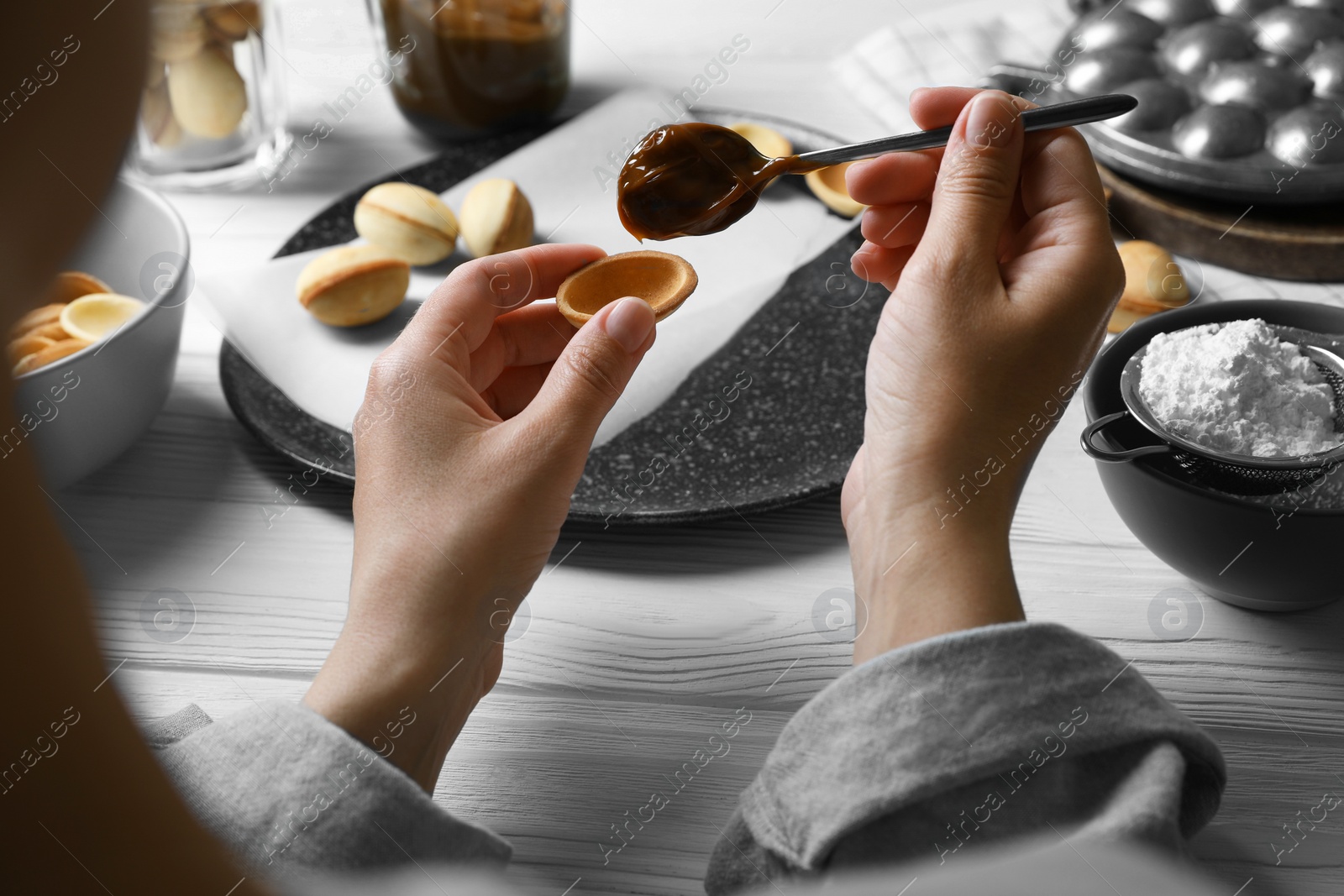 Photo of Woman making delicious walnut shaped cookies at white wooden table, closeup