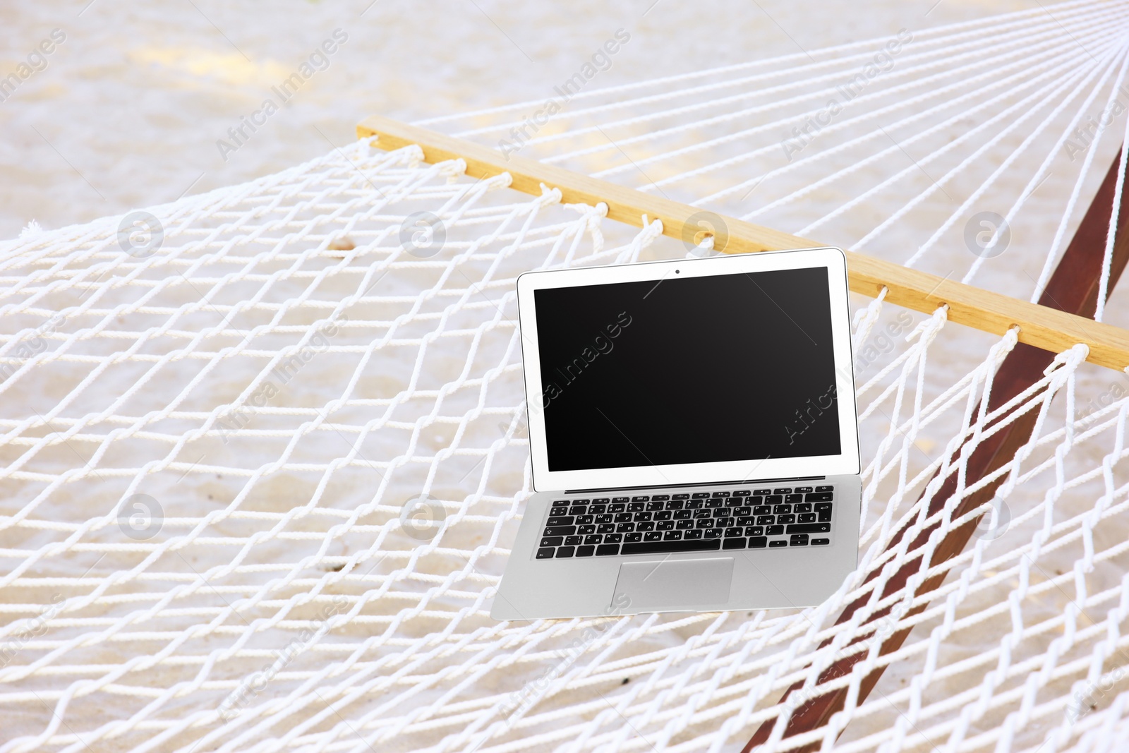 Photo of Comfortable hammock with laptop at seaside. Summer vacation