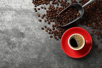 Photo of Cup of aromatic coffee and beans on grey table, flat lay. Space for text