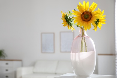 Photo of Beautiful bouquet of sunflowers in vase on table indoors. Space for text