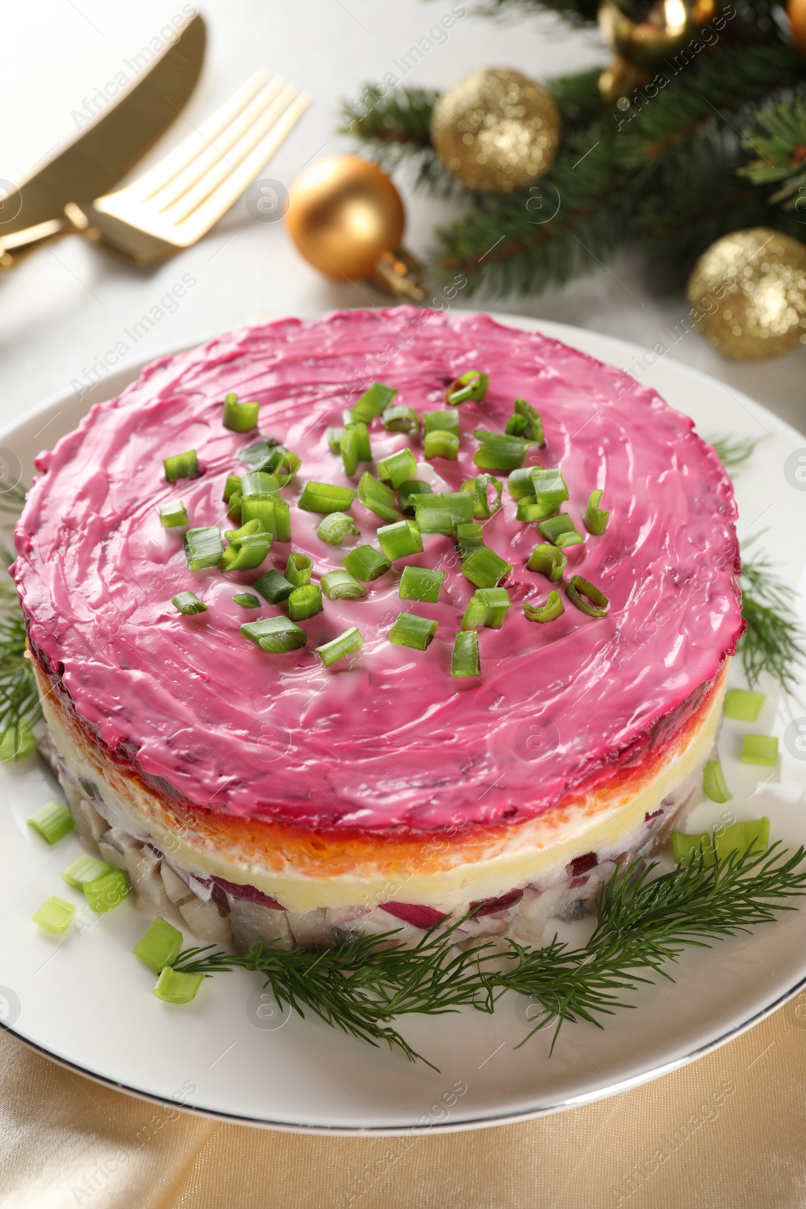 Photo of Herring under fur coat salad and Christmas decor on light grey table, closeup. Traditional Russian dish