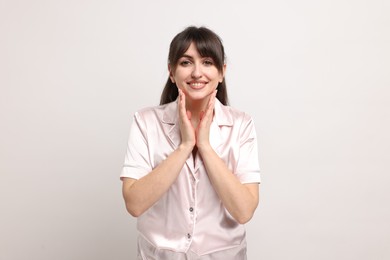 Photo of Happy woman in pyjama on light grey background