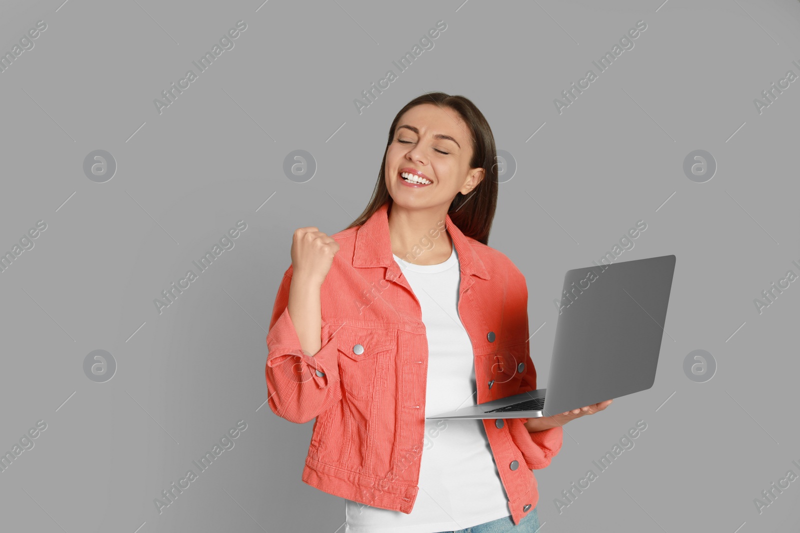 Photo of Young woman with modern laptop on grey background
