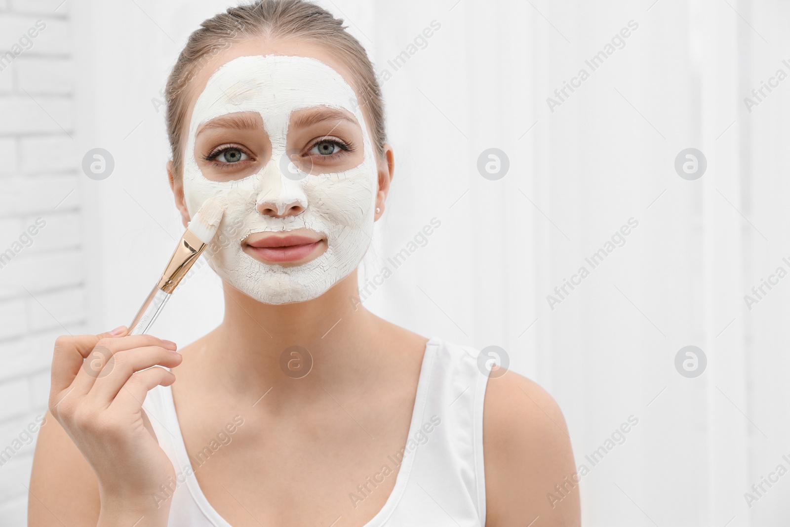 Photo of Beautiful woman applying homemade mask on her face indoors