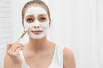Photo of Beautiful woman applying homemade mask on her face indoors