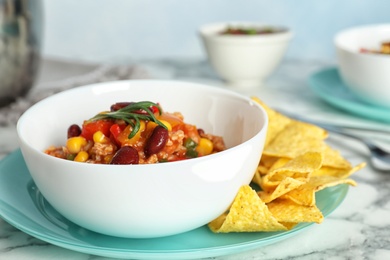 Photo of Bowl with tasty chili con carne served on marble table