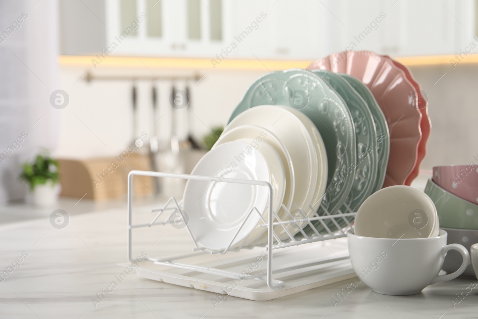 Photo of Many different clean dishware and cups on white marble table in kitchen. Space for text