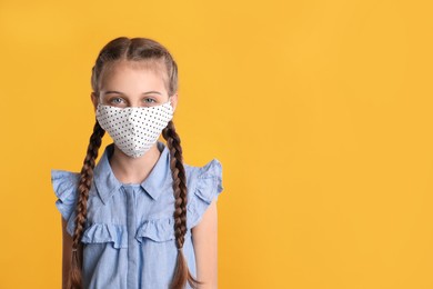Girl wearing protective mask on yellow background, space for text. Child's safety from virus