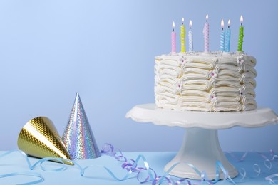 Photo of Delicious cake with burning candles and festive decor on light blue background. Space for text