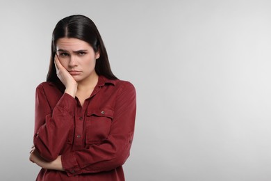 Photo of Sadness. Unhappy woman in red shirt on gray background, space for text