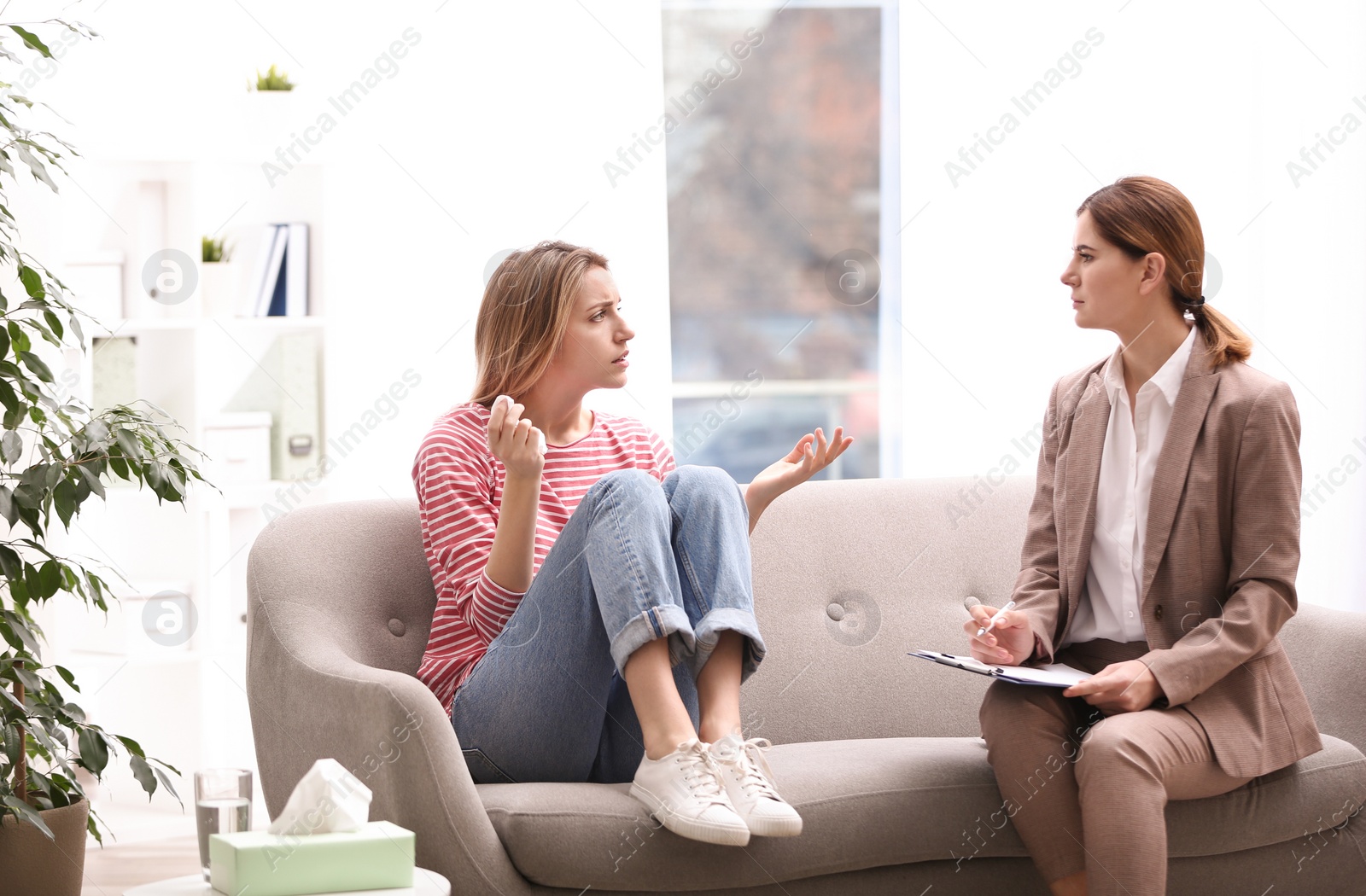 Photo of Psychotherapist working with young woman in light office