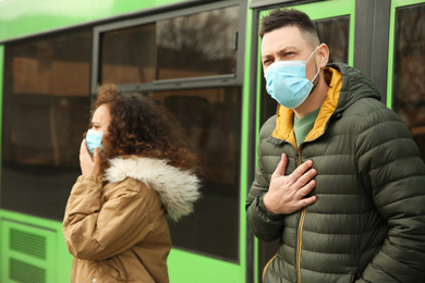 People with disposable masks near bus outdoors. Virus protection