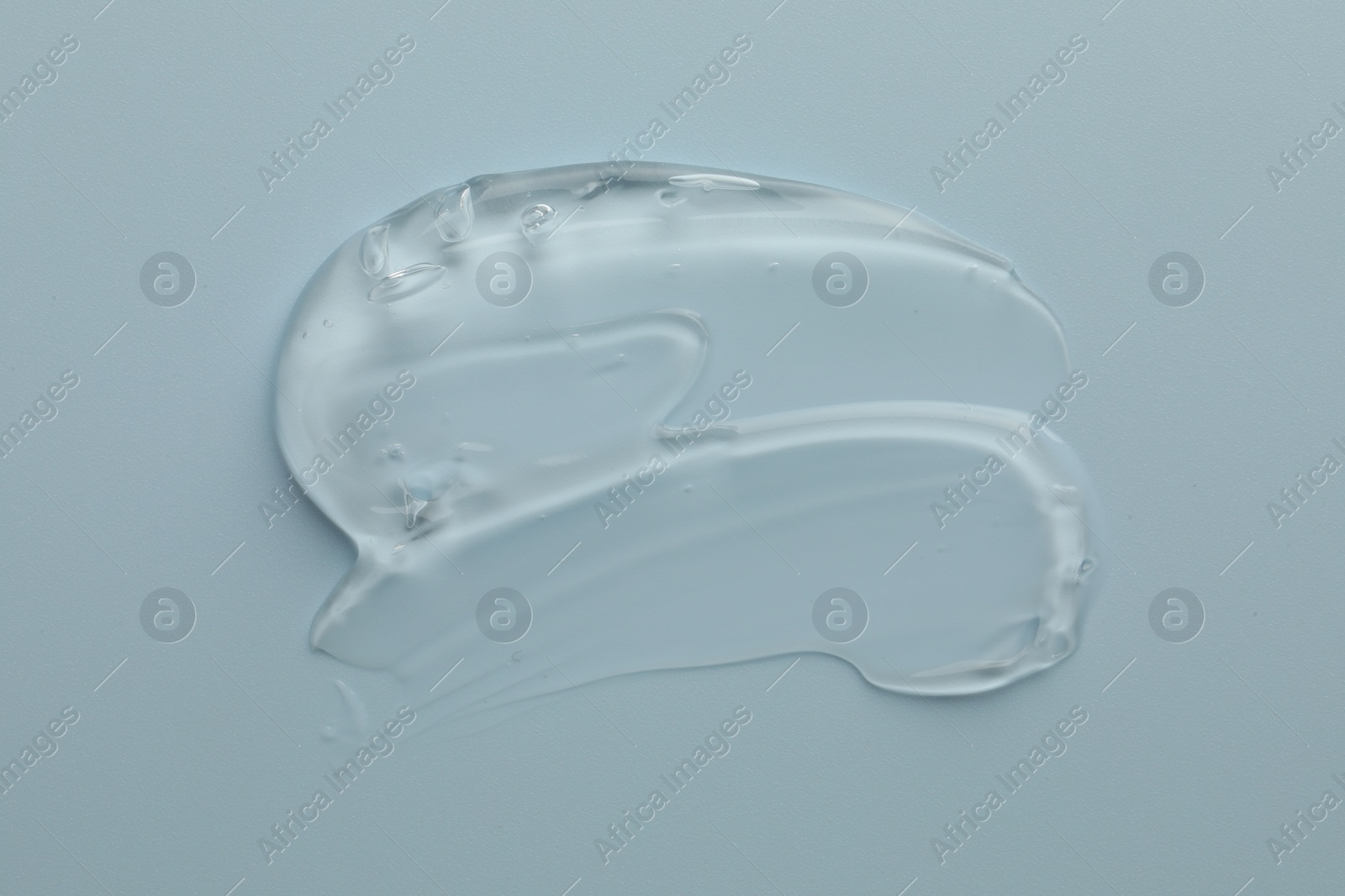 Photo of Smear of clear cosmetic gel on light blue background, top view