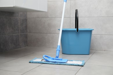 Photo of Mop and bucket on tiled floor in toilet