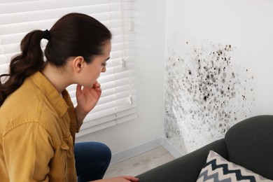 Image of Woman looking at affected with mold walls in room