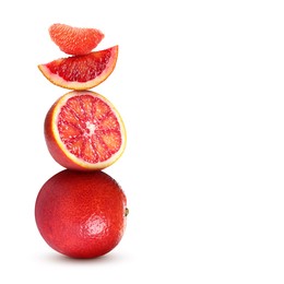 Stacked cut and whole red oranges on white background