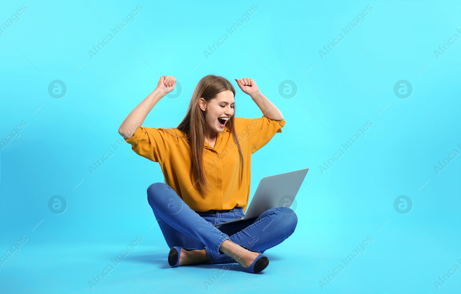 Photo of Emotional young woman with laptop celebrating victory on color background