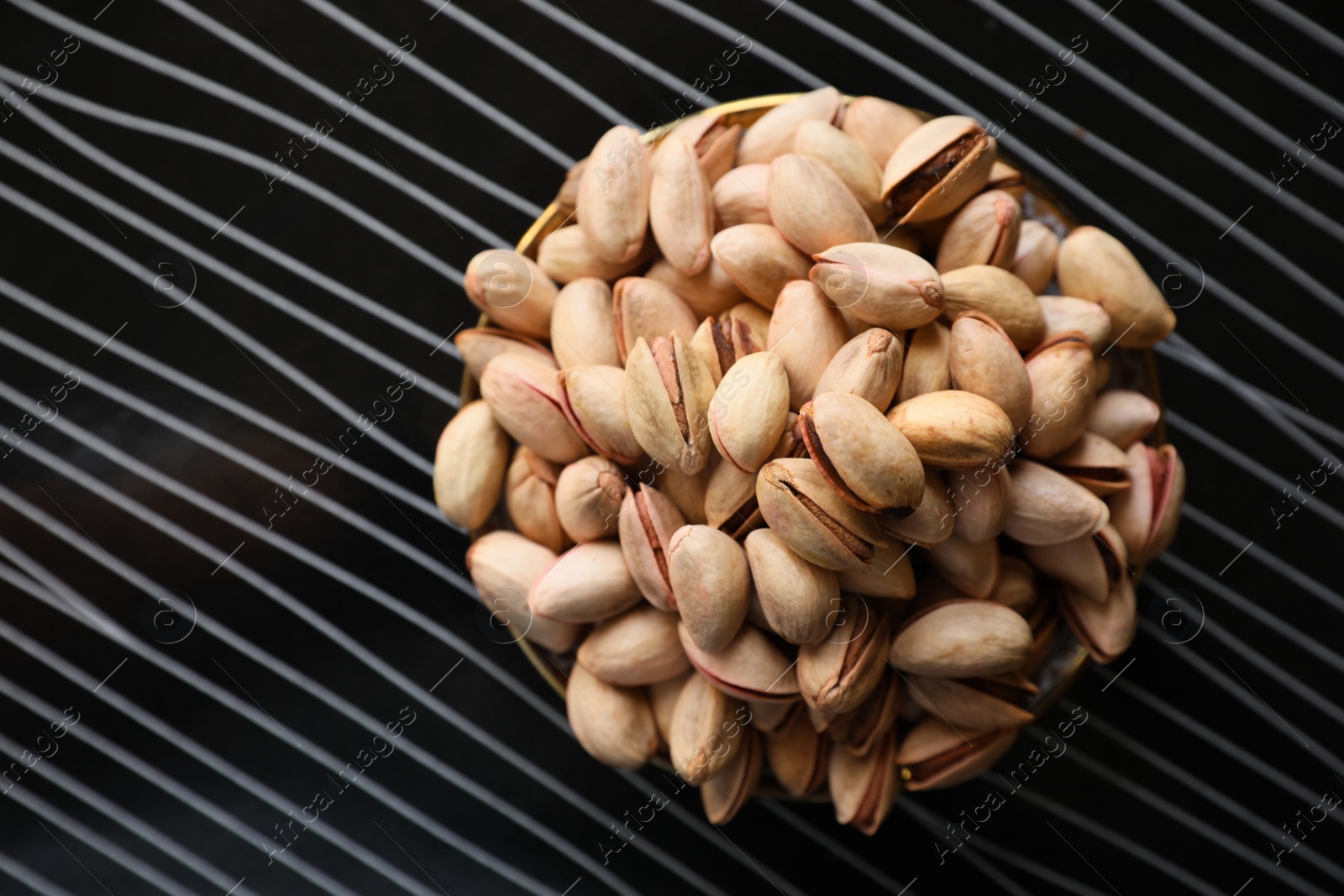 Photo of Many tasty pistachios on black table, top view