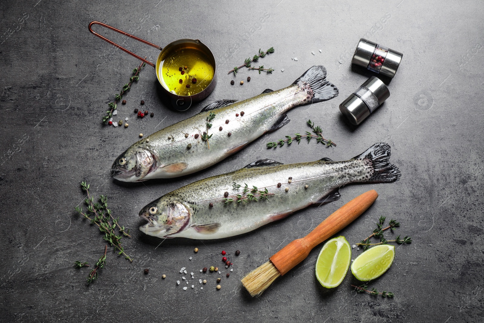 Photo of Flat lay composition with raw cutthroat trout fish on grey table