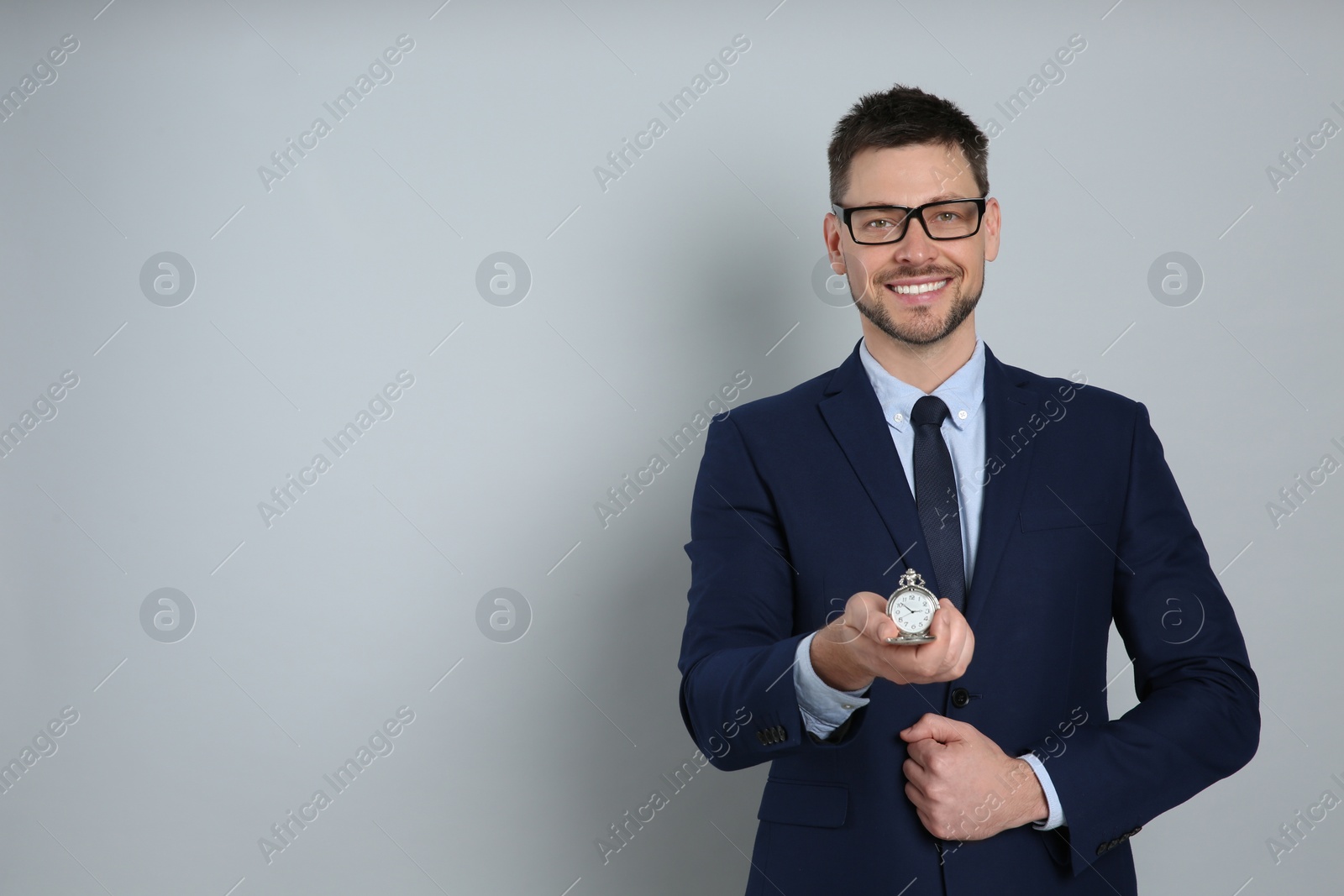 Photo of Happy businessman holding pocket watch on grey background, space for text. Time management