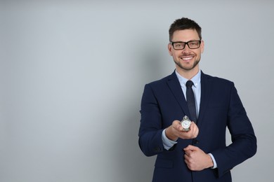 Photo of Happy businessman holding pocket watch on grey background, space for text. Time management