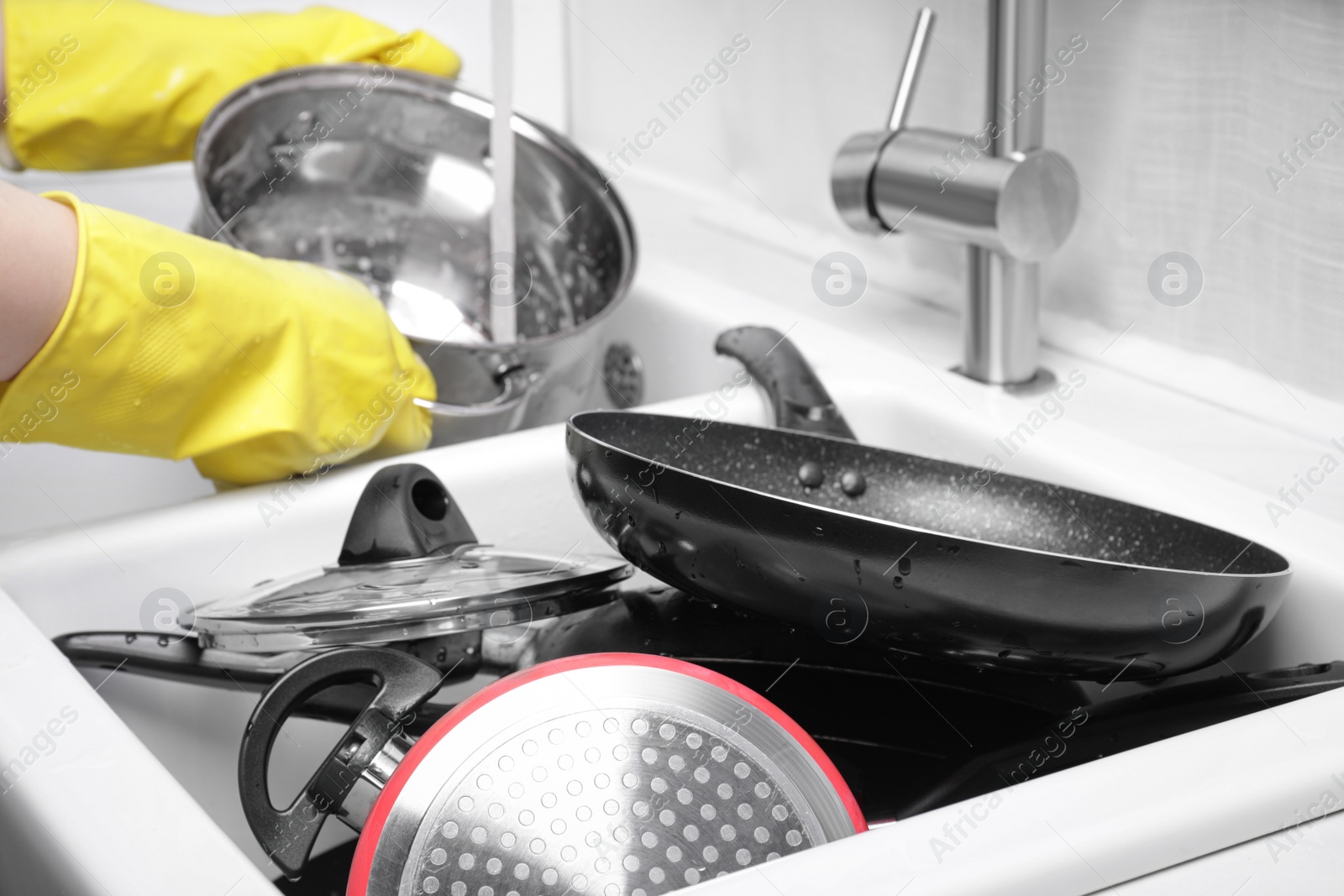 Photo of Woman washing pot in kitchen sink, focus on dirty kitchenware