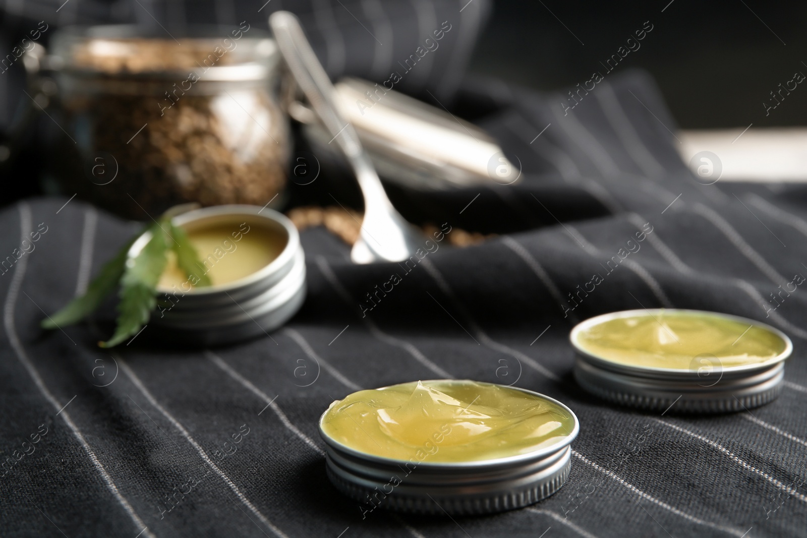 Photo of Containers with hemp lotion on striped fabric