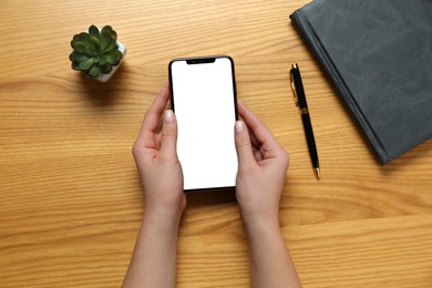 Photo of Woman with smartphone at wooden table, top view