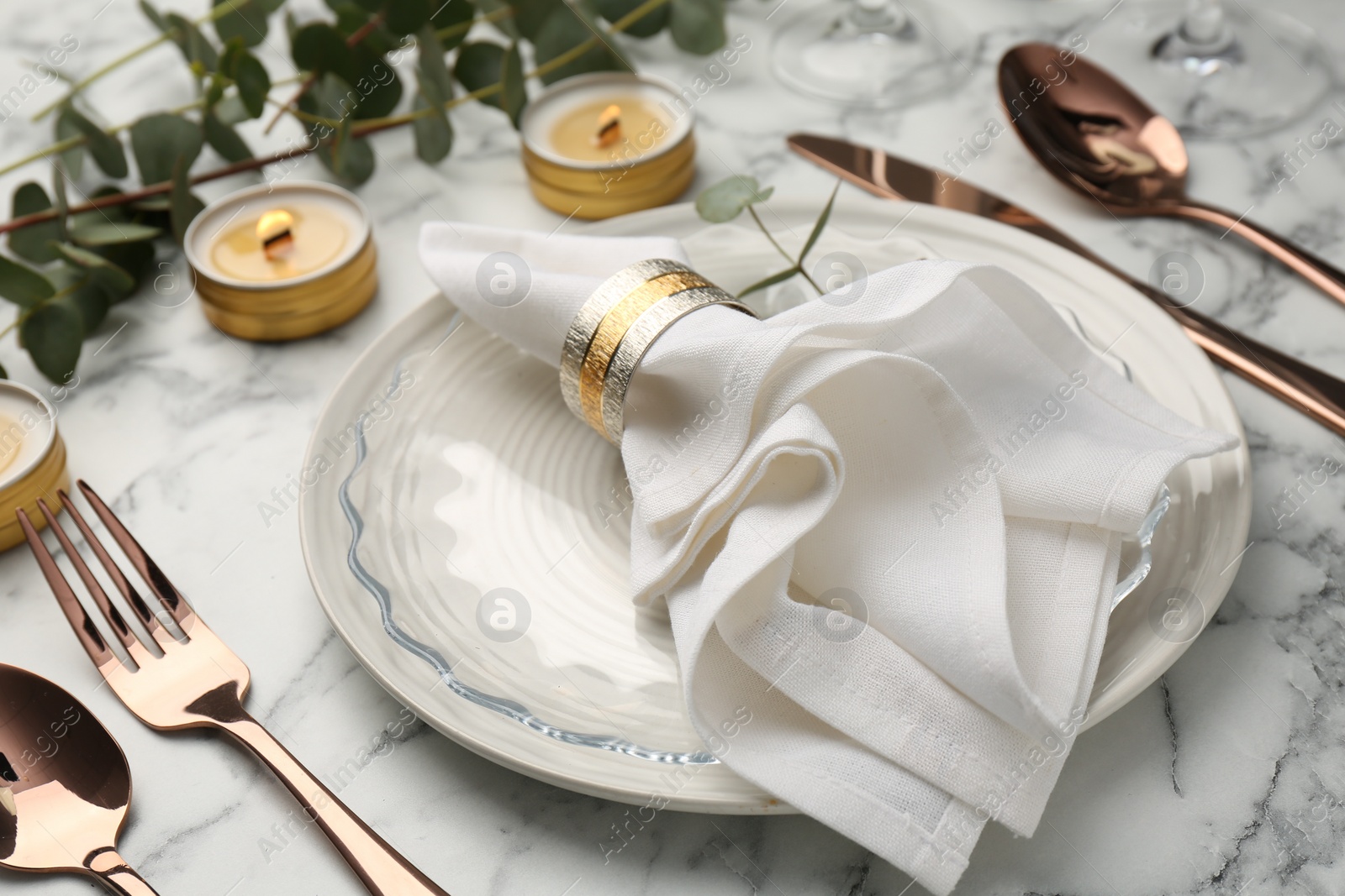 Photo of Beautiful place setting with candles and eucalyptus on white marble table