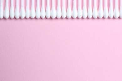 Many cotton buds on pink background, flat lay. Space for text