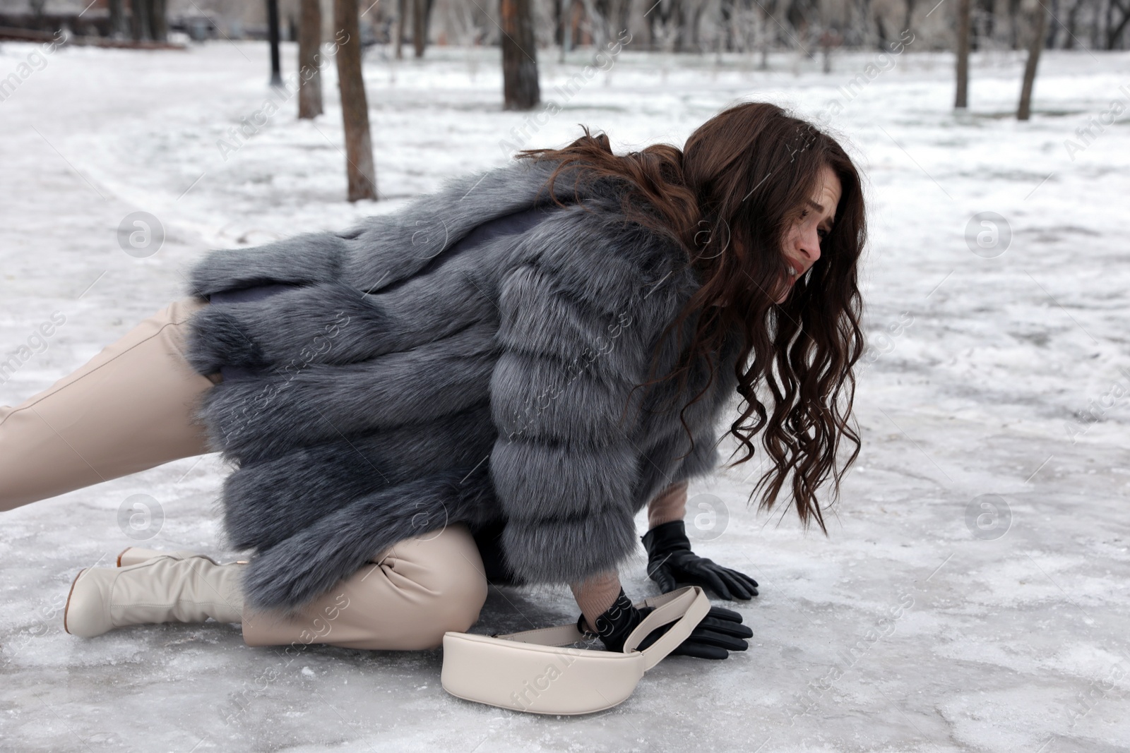 Photo of Young woman fallen on slippery icy pavement in park