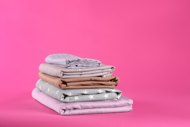 Photo of Stack of clean bed sheets on pink background