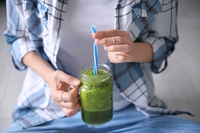 Young woman with mason jar of healthy smoothie, closeup