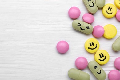 Photo of Different antidepressants with happy emoticons on white wooden table, flat lay. Space for text