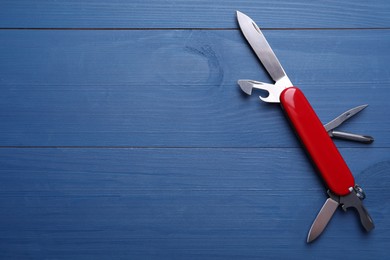 Photo of Modern compact portable multitool on blue wooden table, top view. Space for text