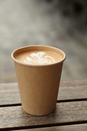 Photo of Takeaway paper cup with coffee on wooden table