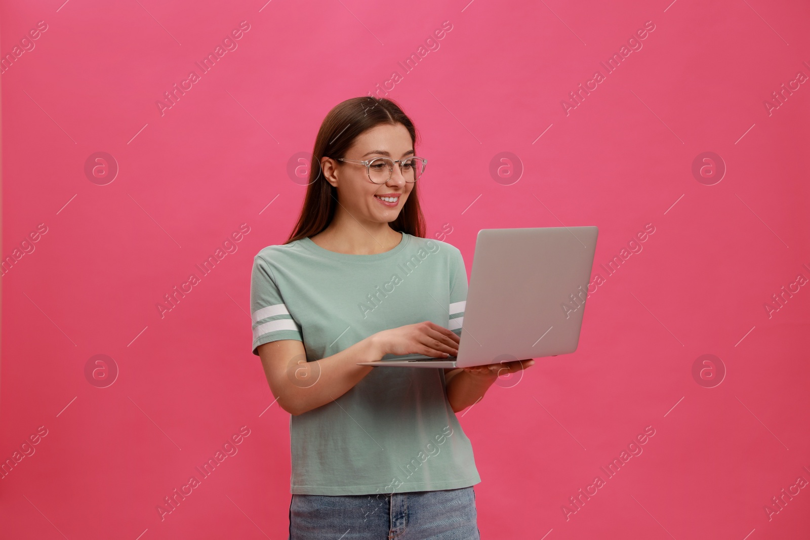 Photo of Young woman with modern laptop on pink background