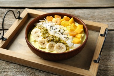 Photo of Tasty smoothie bowl with fresh fruits on wooden table