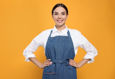 Photo of Young woman in blue jeans apron on yellow background