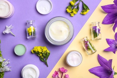 Flat lay composition with jars of body cream on color background