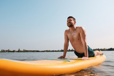 Man practicing yoga on SUP board on river