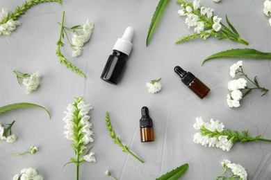 Photo of Flat lay composition with essential oils and flowers on grey background