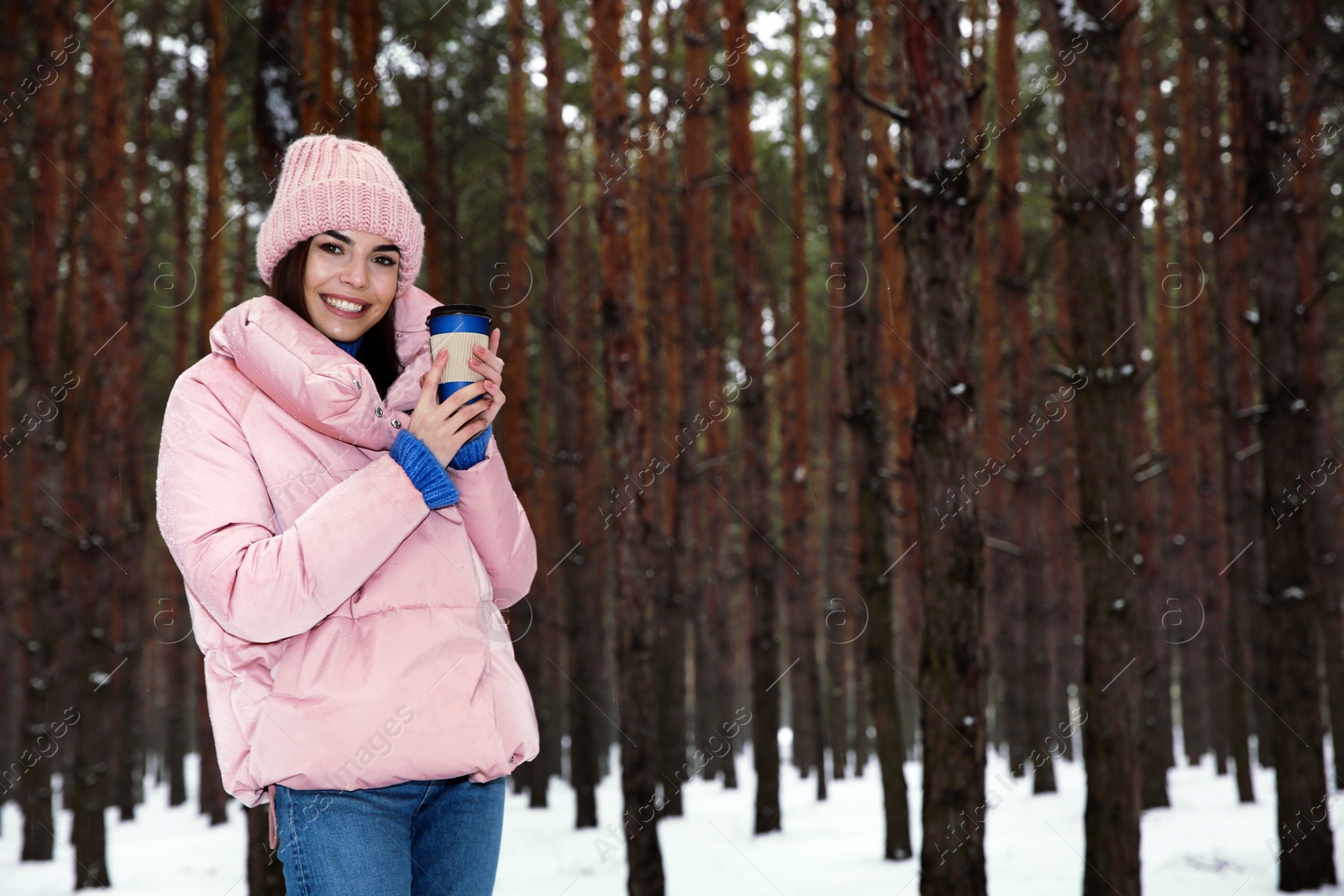 Photo of Young woman with hot drink in snowy winter forest